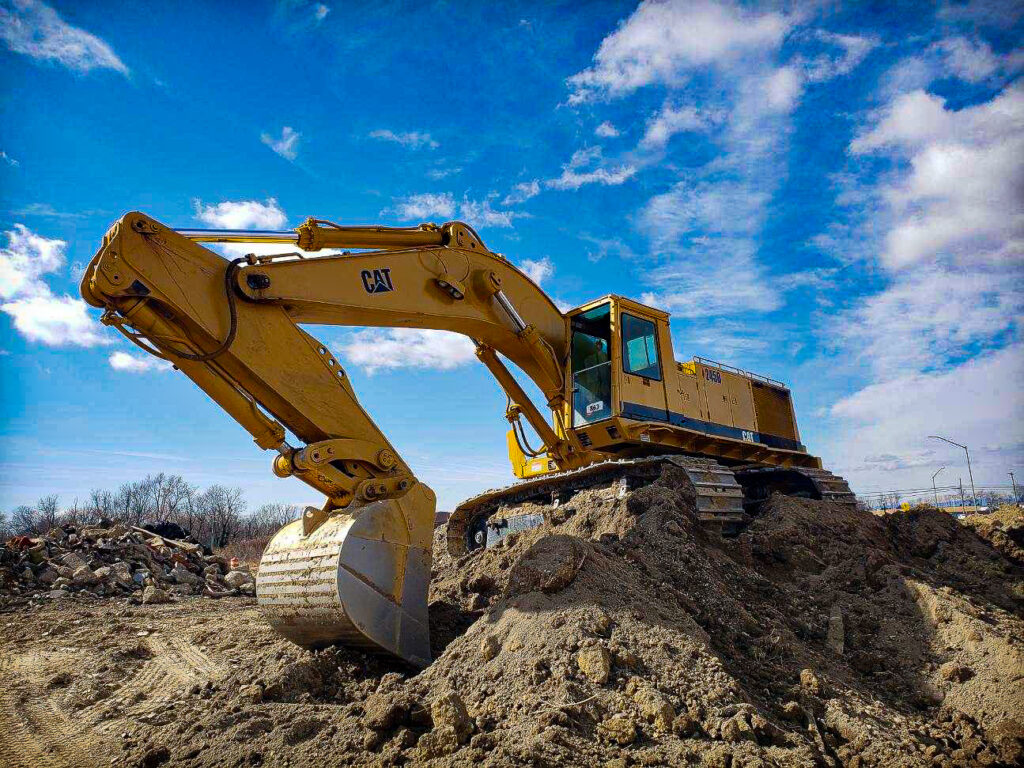 excavator sitting on mound of dirt
