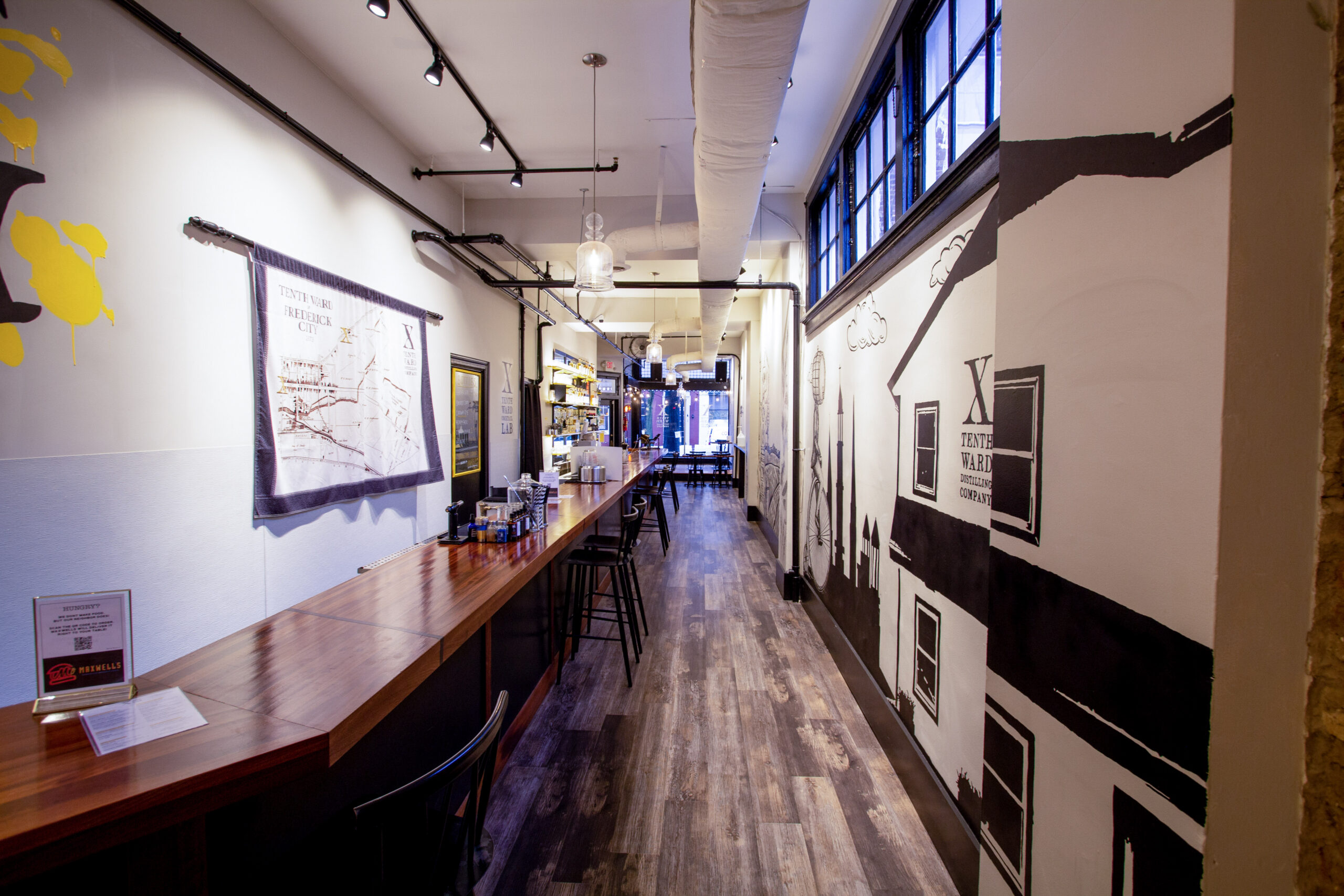 Bar and gallery corridor with framed artwork and wood flooring at Maxwell's