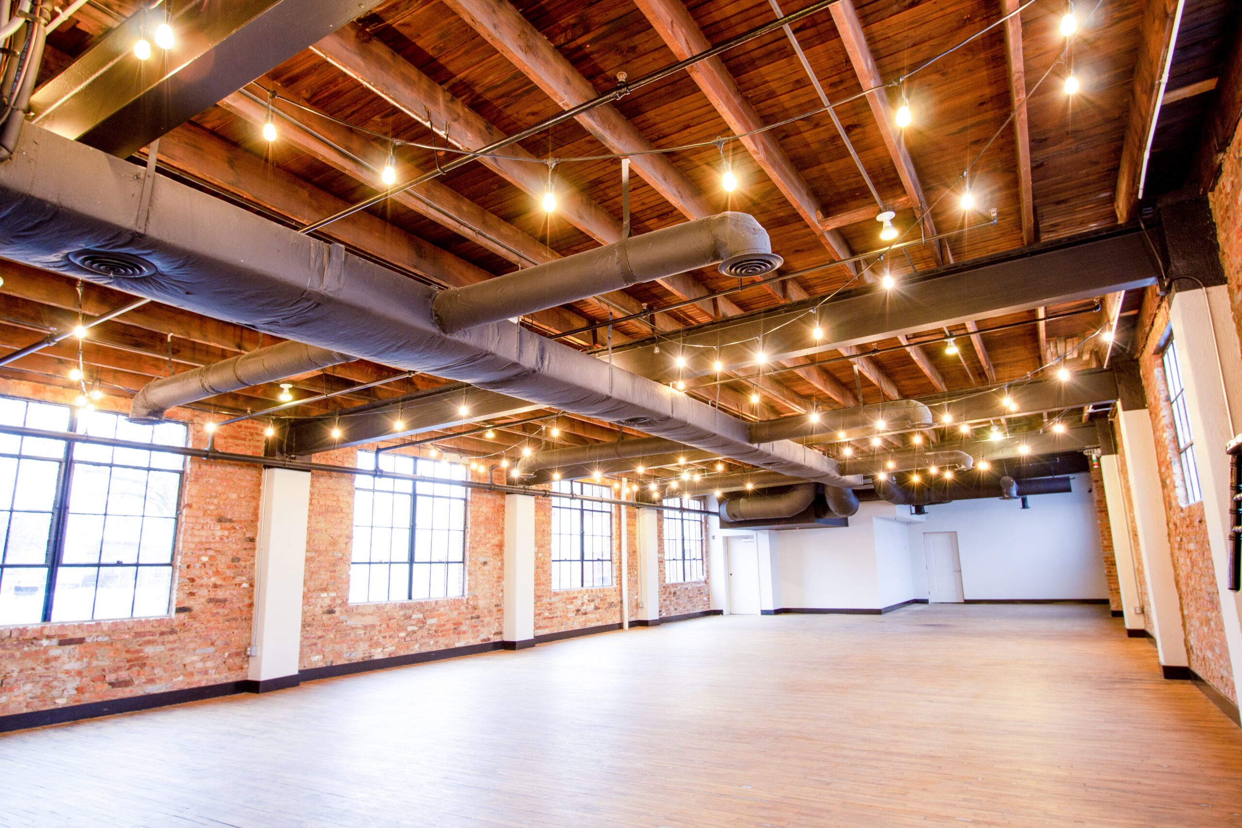 Event space with exposed brick, timber ceiling and festoon lighting at the Patrick Maxwell Building